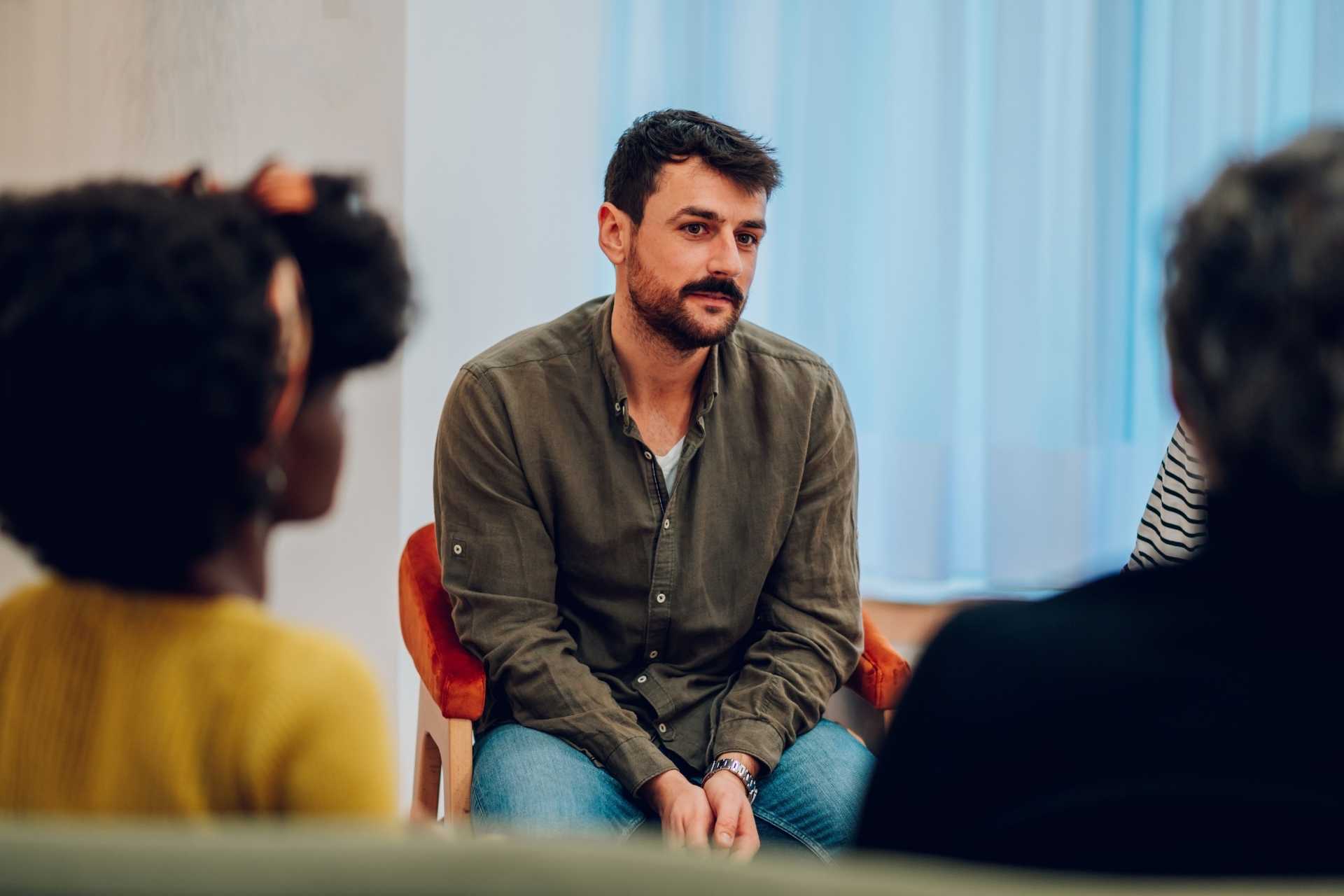 Adult participating in a supportive group therapy session as part of addiction aftercare after rehab.