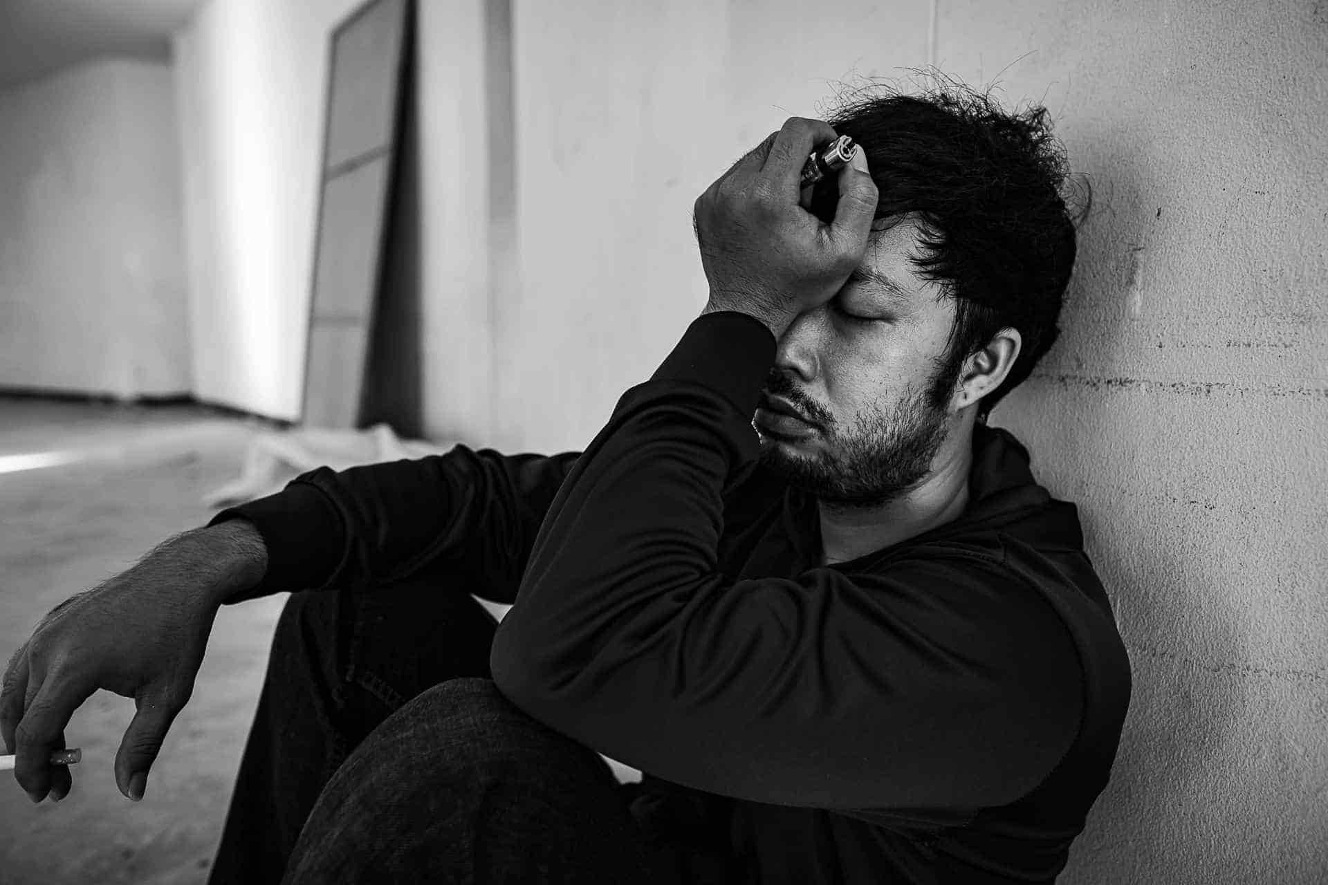 Distressed man sitting against a wall, representing benzodiazepine withdrawal symptoms and the need for medical support.
