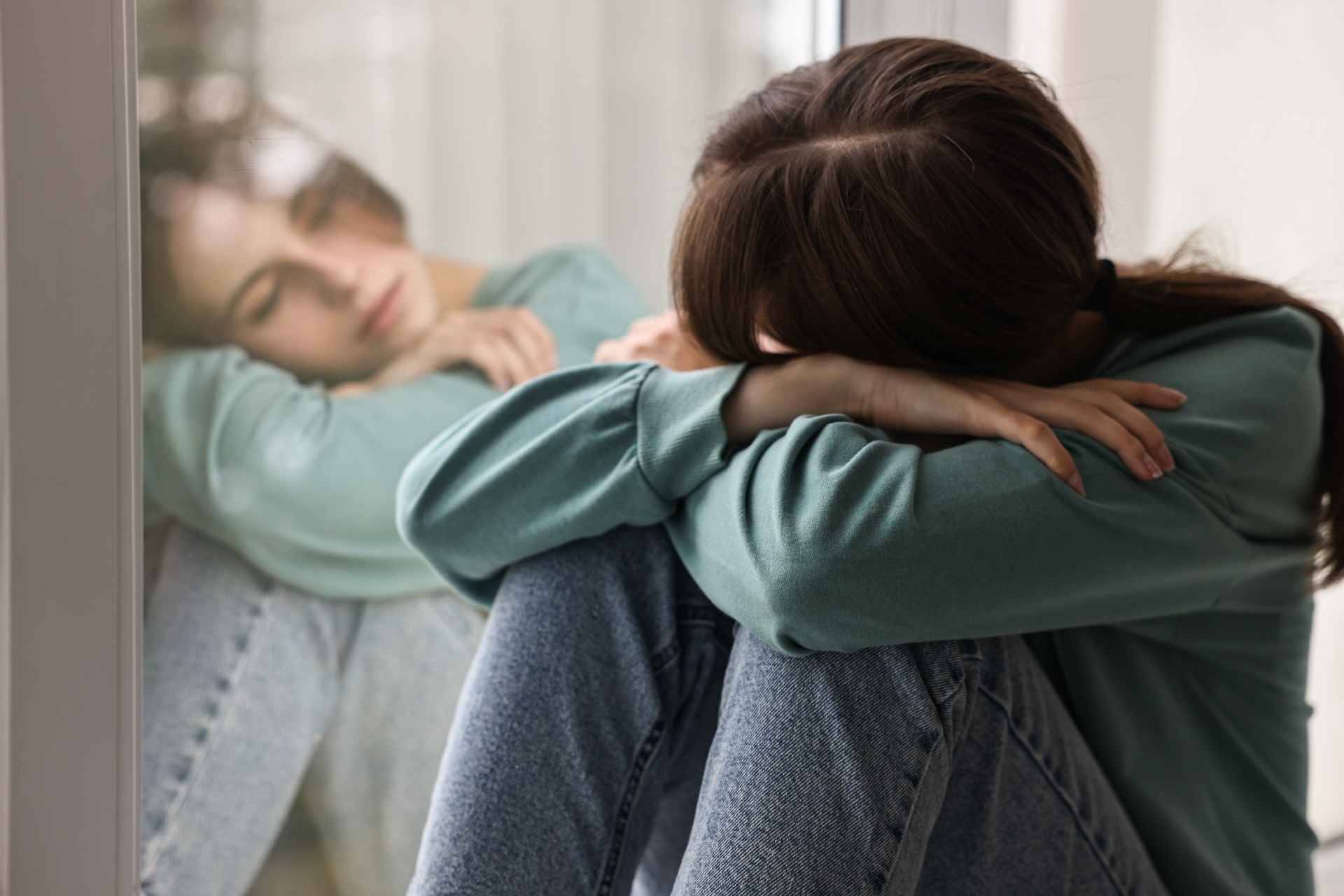 Woman sitting alone with her head down, experiencing low mood.