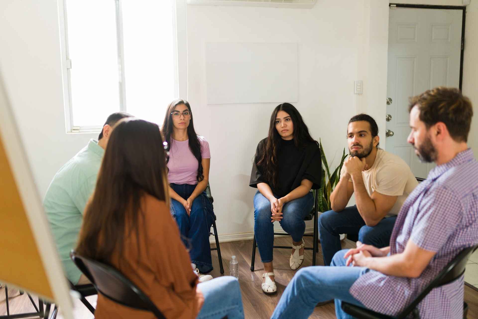 Adults participating in a group therapy session during addiction treatment