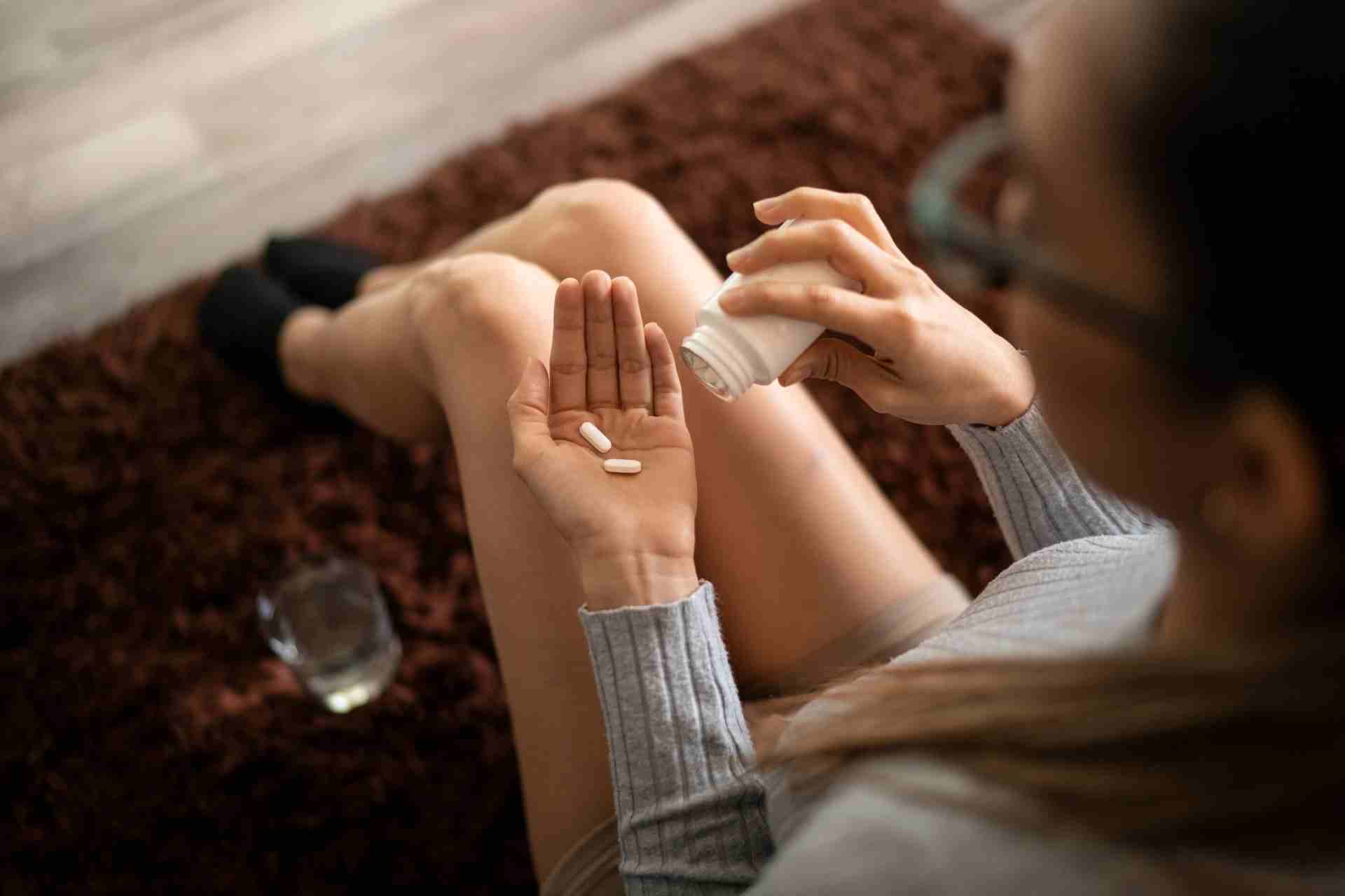 Person holding prescription opioid pills before taking medication from a prescription bottle